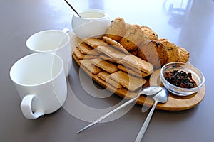 A tasty snack two cups of black tea and a plate of oatmeal cookies a wooden board on the gray background, leaf tea.