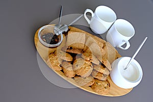 A tasty snack two cups of black tea and a plate of oatmeal cookies a wooden board on the gray background, leaf tea.