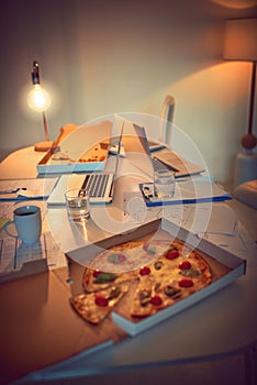 Tasty snacks to see you through the night. Still life shot of pizza on a desk in an office.