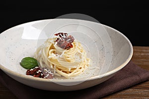 Tasty spaghetti with sun-dried tomatoes and cheese on wooden table, closeup. Exquisite presentation of pasta dish