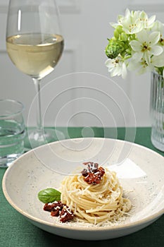 Tasty spaghetti with sun-dried tomatoes and parmesan served on table, closeup. Exquisite presentation of pasta dish