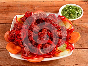 Tasty and spicy deep fried Chicken 65 served on wooden background. Dishes and appetizers of indian cuisine, selective focus