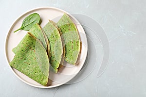 Tasty spinach crepes on grey marble table, top view. Space for text