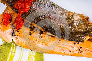 Tasty steak of fried rainbow trout fillet with sauces on plate