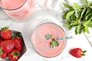 Tasty strawberry smoothie with mint in glass on marble table, flat lay