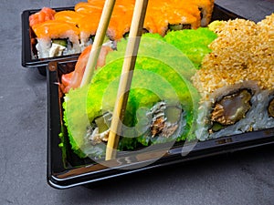 Tasty sushi bar, Eating Sushi with chopsticks. California Sushi roll set with salmon, vegetables, fish, caviar closeup. Japan