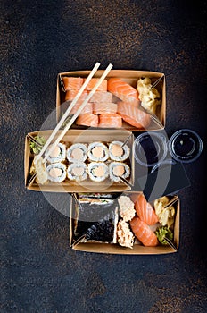 Tasty sushi rolls in disposable kraft paper boxes, sauces, chopsticks. Food for take away or delivery