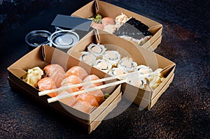 Tasty sushi rolls in disposable kraft paper boxes, sauces, chopsticks. Sushi for take away or delivery