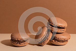 Tasty sweet brown macaroons with chocolate filling on beige background. Homemade delicious. Close-up view