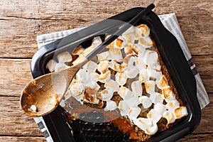 Tasty sweet potato casserole with nuts topped with marshmallows close-up in a baking dish. Horizontal top view