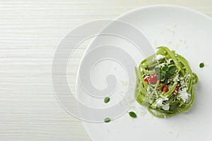 Tasty tagliatelle with spinach and cheese served on white wooden table, top view and space for text. Exquisite presentation of