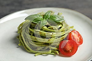 Tasty tagliatelle with spinach and tomatoes on plate, closeup. Exquisite presentation of pasta dish