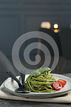 Tasty tagliatelle with spinach and tomatoes served on grey table in restaurant, closeup. Exquisite presentation of pasta dish