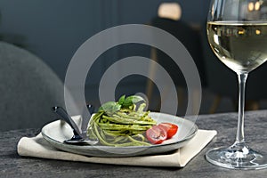 Tasty tagliatelle with spinach and tomatoes served on grey table in restaurant, closeup. Exquisite presentation of pasta dish