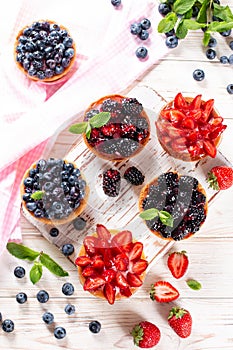 Tasty tartlets with berries on wooden table, top view
