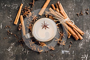 Tasty tea mith milk and spices on the rustic background