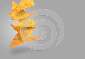 Tasty tortilla chips falling on grey background