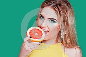 Tasty tropical fruits! Attractive sexual woman with beautiful makeup and wet hair eating fresh juicy grapefruit or orange smiling