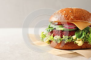 Tasty vegetarian burger with beet cutlet on table against light background.