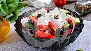 Tasty  vitamin salad with fresh vegetables, goat cheese, black olives, basil sauce on a white plate on a wooden background