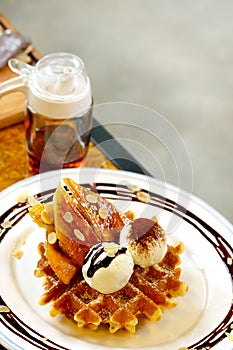 Tasty waffle and vanilla ice cream set served with banana sugar coating Topped with chocolate sauce on white plate in green garden