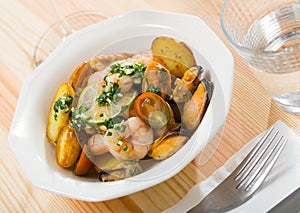 Tasty warm salad with fried potatoes, shrimp and mussels, served at plate