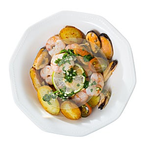 Tasty warm salad with fried potatoes, shrimp and mussels, served at plate