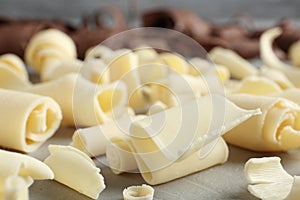 Tasty white chocolate curls on table