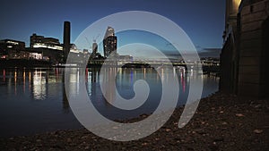 Tate Modern and London city skyline with lights lit up at night on the River Thames beach at low tid