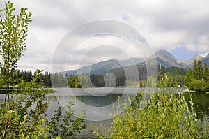 Krajina panorama Tater se zelenou trávou a bílými mraky. Jezero a voda v popředí. Slovenský národní park.