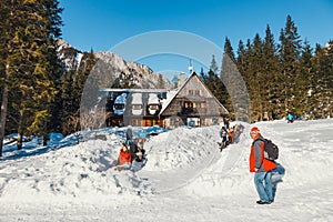 Group of tourists sit in front of a mountain hut and enjoy the sun, Koscieliska Valley