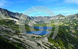 Tatra mountains in Poland, green hill, lake and rocky peak in the sunny day with clear blue sky photo