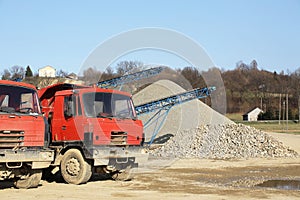 Tatra`s red dump truck in the background of rubble sorting. Elements of equipment for the extraction and sorting of rubble.