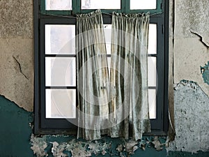 Tattered old curtains across the window of a room in an abandoned warehouse