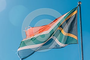 Tattered South African Flag Waving Against a Clear Blue Sky During Daytime