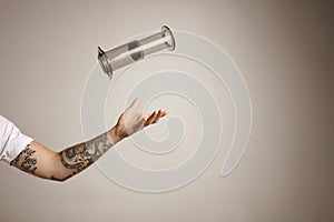 Tattoed man`s arm throwing and catching aeropress