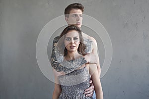 Tattoed stylish guy hugging his beautiful girlfriend