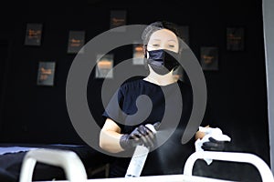 Tattoo artist disinfects the work surface, conducts preparatory work for permanent makeup. tattoo artist girl in black mask