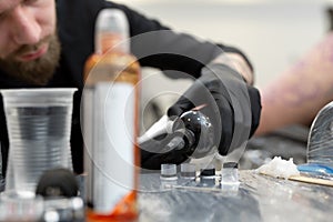 Tattoo artist prepares tools and ink before working in a tattoo parlor.