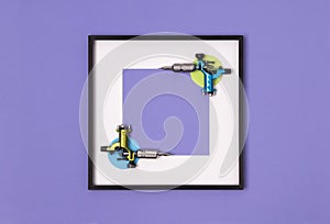 Tattoo machines in frame on purple background. Mock up for tattooing artist studio