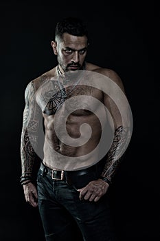 Tattoo model with six pack and ab. Bearded man with tattooed body. Man with bare torso in jeans. Athlete or