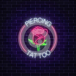 Tattoo and piercing parlor glowing neon signboard with rose emblem. Flower symbol in circle frame with text.