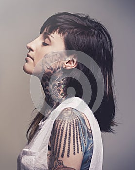 Tattoo, profile and woman with culture, rebel and confident person on a grey studio background. Face, girl and unique