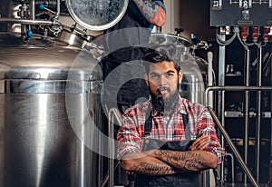 Tattooed, bearded Caucasian and Indian men in the craft beer microbrewery.