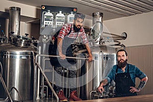 Tattooed, bearded Caucasian and Indian men in the craft beer microbrewery.