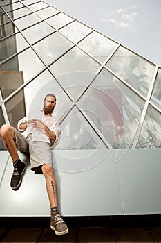 Tattooed and bearded hipster in front of office building