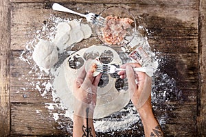 Tattooed chef`s hands cooking russian dumplings on wooden table