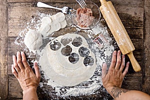 Tattooed chef`s hands cooking russian dumplings on wooden table