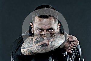 Tattooed elbow hide male face dark background. Visual culture concept. Tattoo can function as sign of commitment. Do