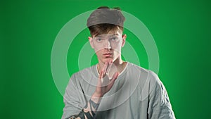 Tattooed man gesturing with finger on his lips over green background